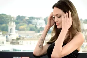 Vêtue d'une robe en cuir ultra moulante, Angelina Jolie adopte une attitude totalement sexy pour séduire les photographes.