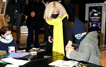 Brigitte Macron rayonnante dans un long manteau noir aux côtés de Didier Deschamps pour le lancement de l'opération Pièces Jaunes