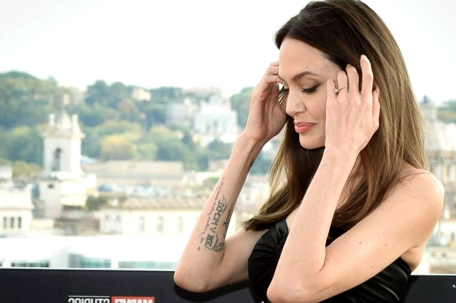 Vêtue d'une robe en cuir ultra moulante, Angelina Jolie adopte une attitude totalement sexy pour séduire les photographes.