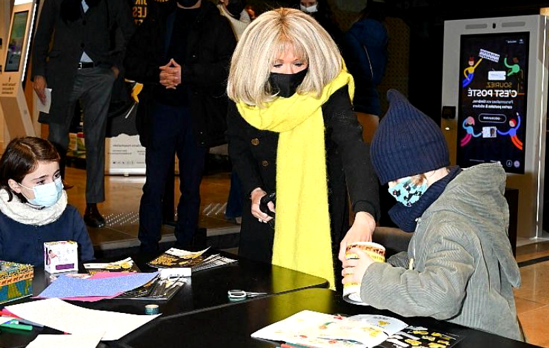 Brigitte Macron rayonnante dans un long manteau noir aux côtés de Didier Deschamps pour le lancement de l'opération Pièces Jaunes